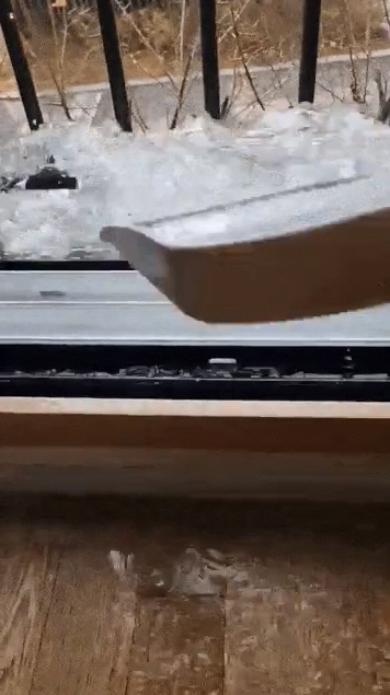 동탄레이크자이 아파트의 한 주민이 바닥에 가득 고인 물을 쓰레받기로 창문 밖으로 퍼내고 있다. [온라인커뮤니티 캡처]